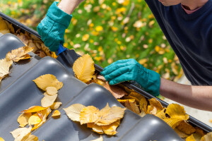 A man cleaning his gutters to prepare his North Texas home for winter.