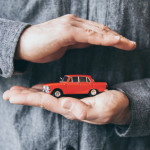 Male,Hands,Holding,And,Protecting,A,Red,Toy,Car.,Conceptual