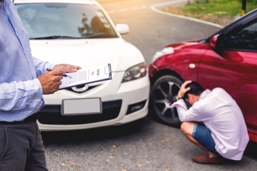 Insurance,Agent,Writing,On,Clipboard,While,Examining,Car,After,Accident